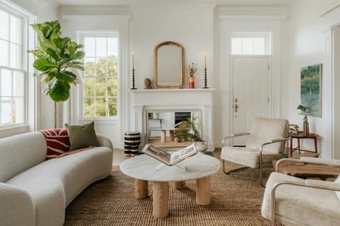 Salón luminoso con paredes blancas lisas, grandes ventanas y mobiliario en tonos neutros